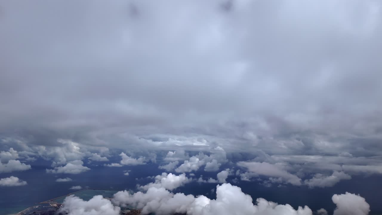 an immersive pilot view from an airplane cockpit while flying between layers of white cottony clouds over Valencia City and Harbor.