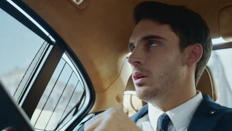 un hombre profesional molesto leyendo datos en una tableta en el coche de negocios.