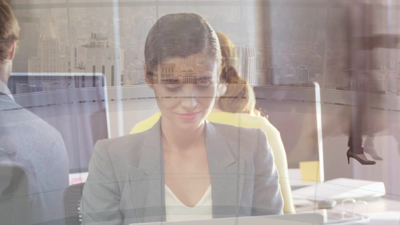 Seated woman working at laptop, typing in office, walkers creating ghosted figures across desk
