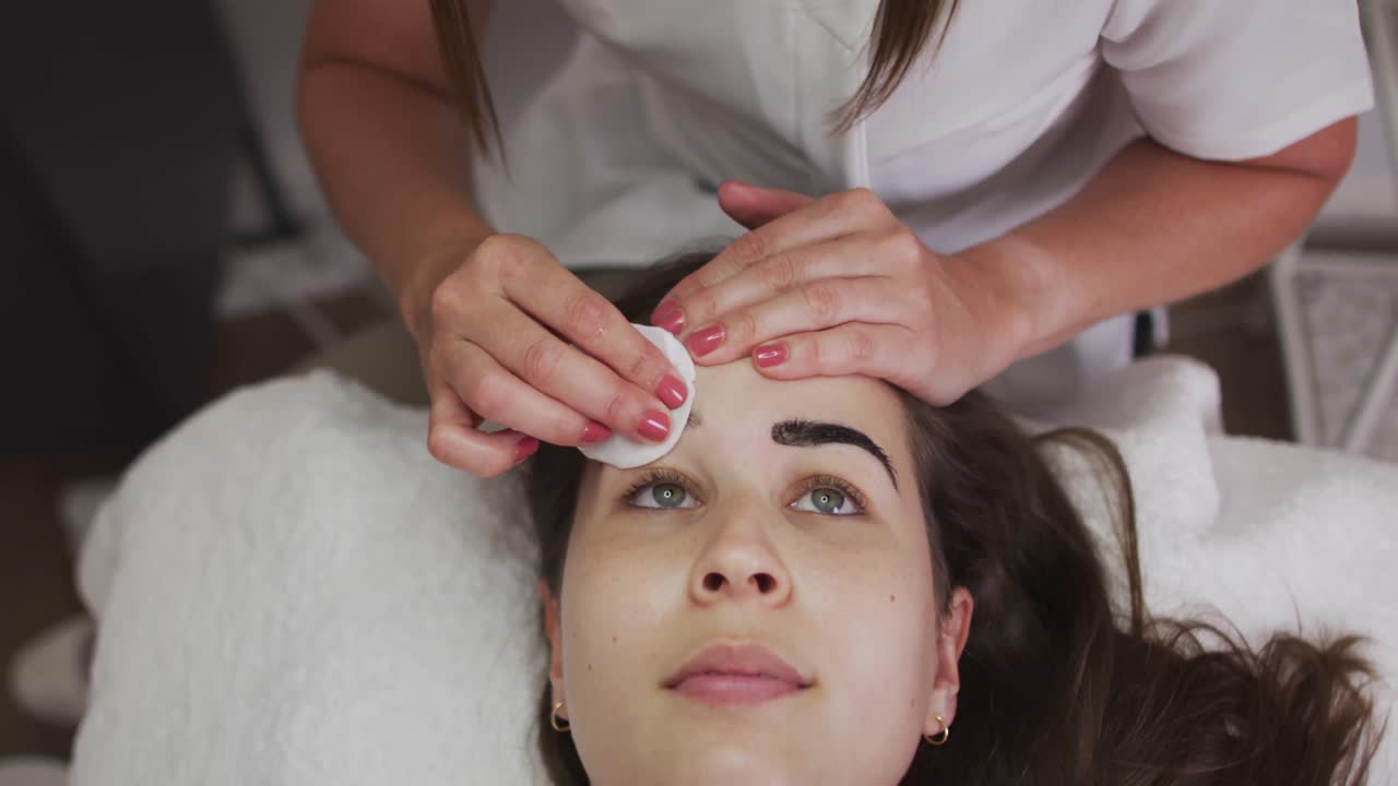 Mulher caucasiana usando máscara facial deitada tingindo as sobrancelhas