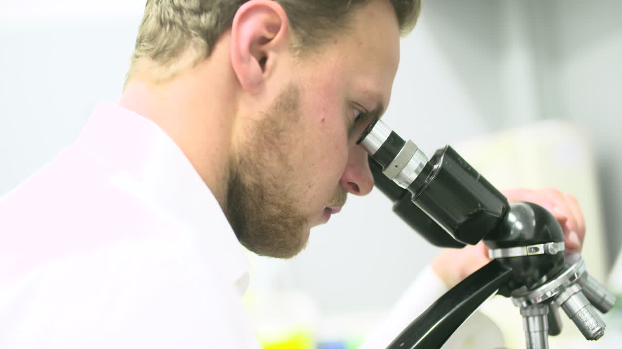 Man Looking Through a Microscope in a Science Laboratory