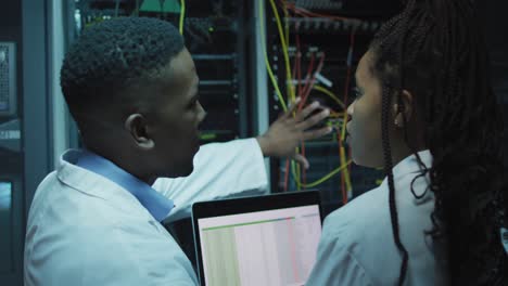 técnicos informáticos afroamericanos que usan tabletas trabajando en la sala de servidores de negocios