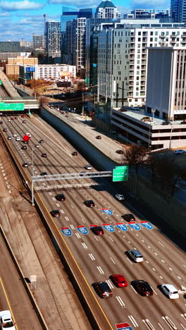 multiple vehicles going by the busy wide-lane highways in atlanta downtown. view on the city scenery on sunny day from top. vertical video