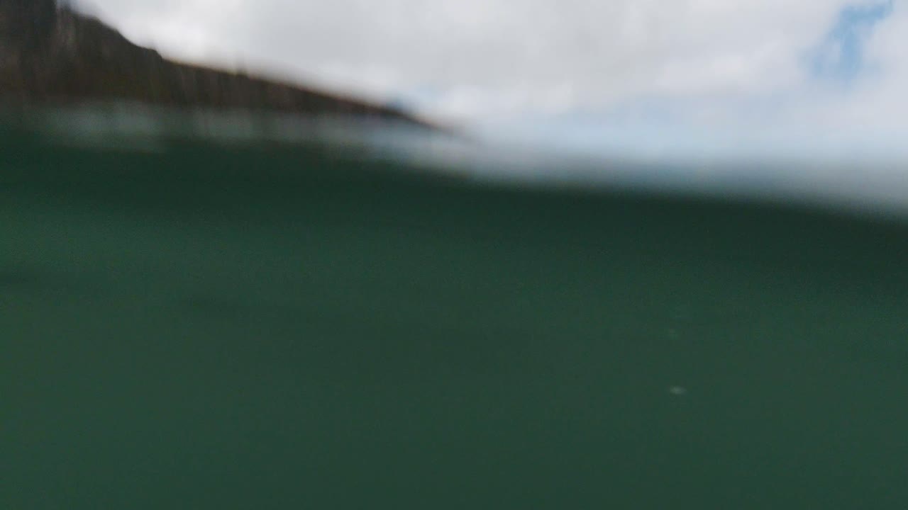 cámara sumergiéndose suavemente bajo el agua debajo de las olas tranquilas en cámara lenta