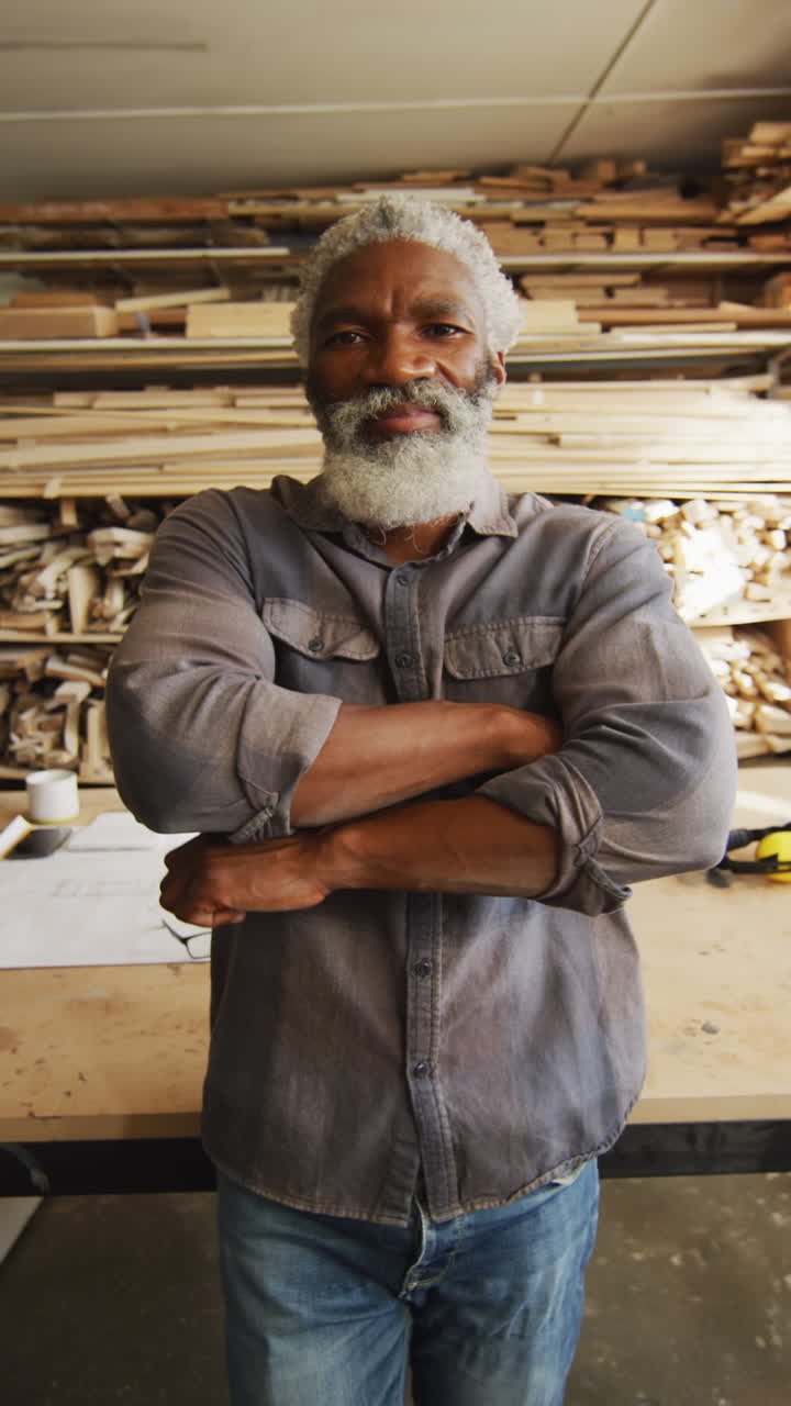 video vertical de un carpintero afroamericano feliz sonriendo a la cámara en el taller