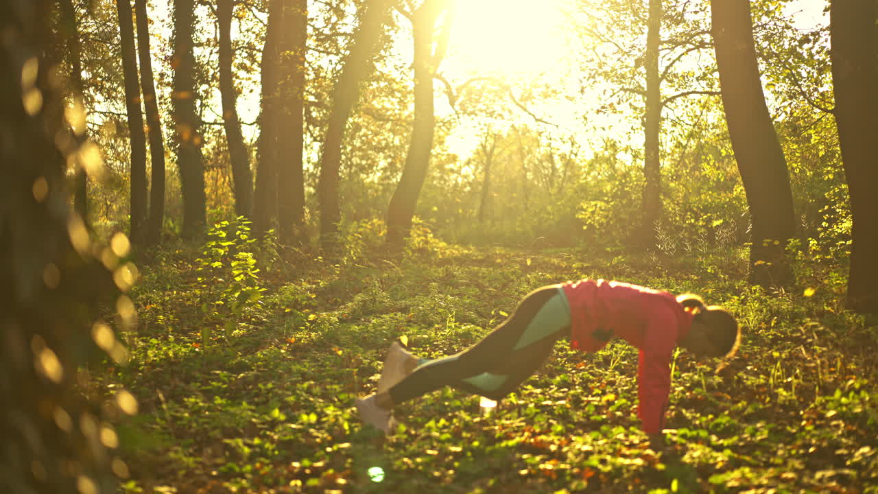 Woman exercising and stretching in a sunny autumn forest
