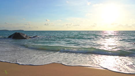 Wellen-Rollen-An-Einem-Tropischen-Strand-Heran,-Während-Die-Sonne-Am-Westlichen-Himmel-Untergeht