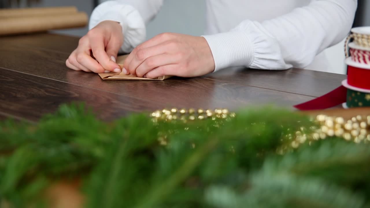 美丽的年轻女人的手在棕色纸上包裹圣诞礼物