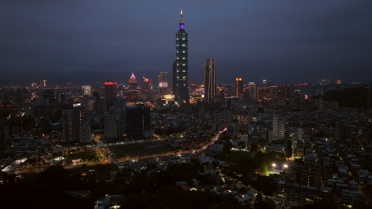 Aerial backwards shot of skyline in Taipei city with billboards and 101 tower at night