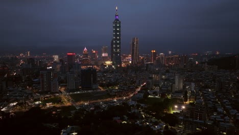 aerial backwards shot of skyline in taipei city with billboards and 101 tower at night