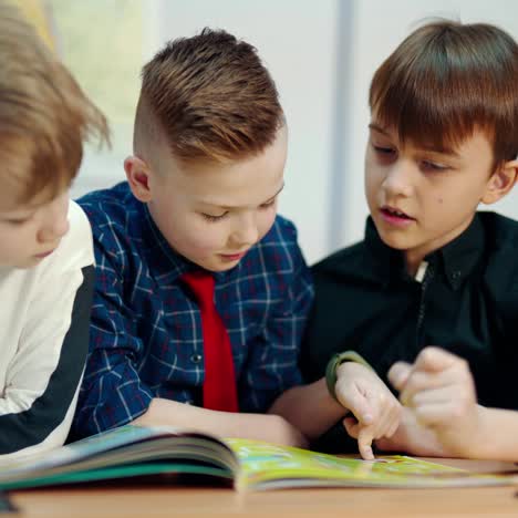 schoolboys in the classroom. children reading a book together in elementary school. education concept.