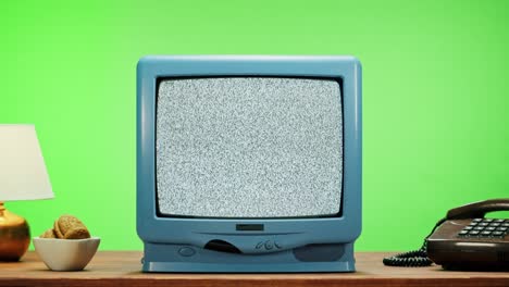 vieja televisión con pantalla gris sobre fondo verde cromado. primer plano de la televisión vintage en la mesa con teléfono retro, nostalgia