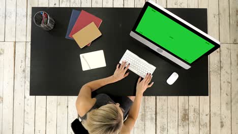mujer joven trabajando en su escritorio de la oficina con la computadora. pantalla verde muestra de maqueta