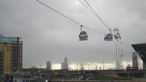 cable cars carry passengers across the sky as a double-decker bus passes
