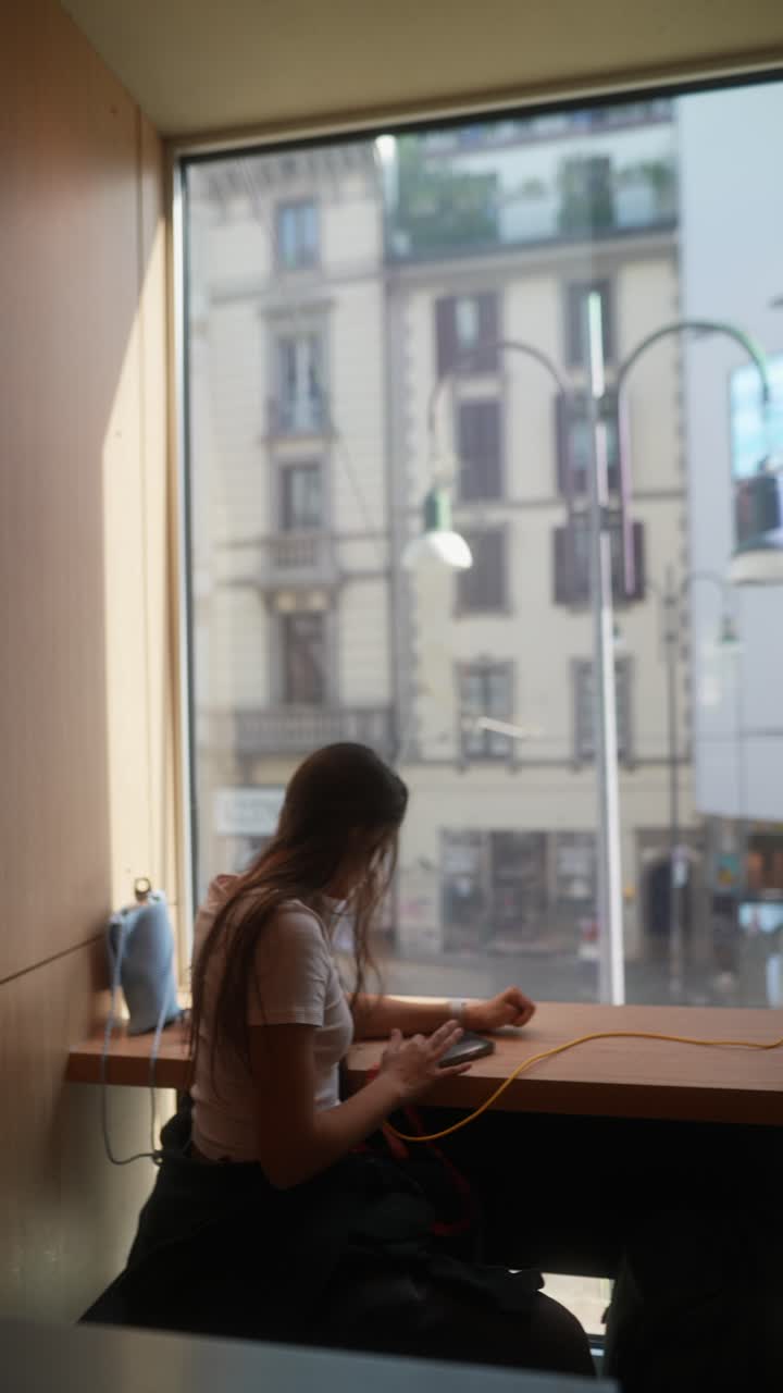 Woman working on her phone in a cafe by a window