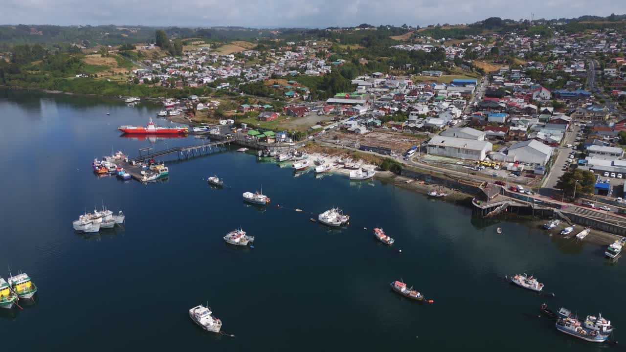 Aerial view of Dalcahue showcasing the port, fishing boats, and scenic coastal city. dolly forward