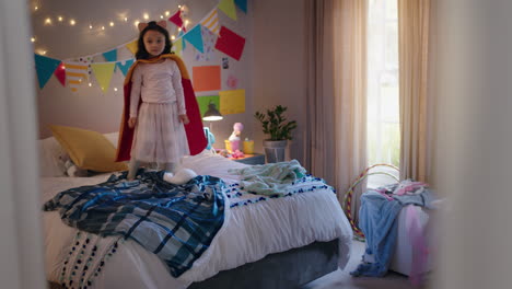 niña feliz saltando en la cama vistiendo disfraz jugando a un juego disfrutando de la imaginación juguetona en un dormitorio colorido en casa