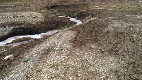 lecho de arroyo seco con agua que fluye a través de grietas en la tierra