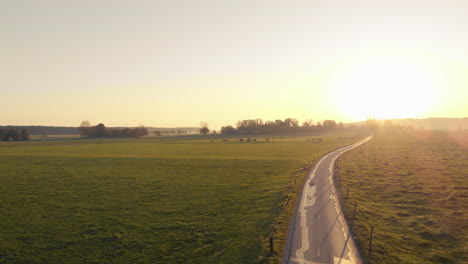 aerial clip of a field and a little road in the bavarian alps area, during sunset