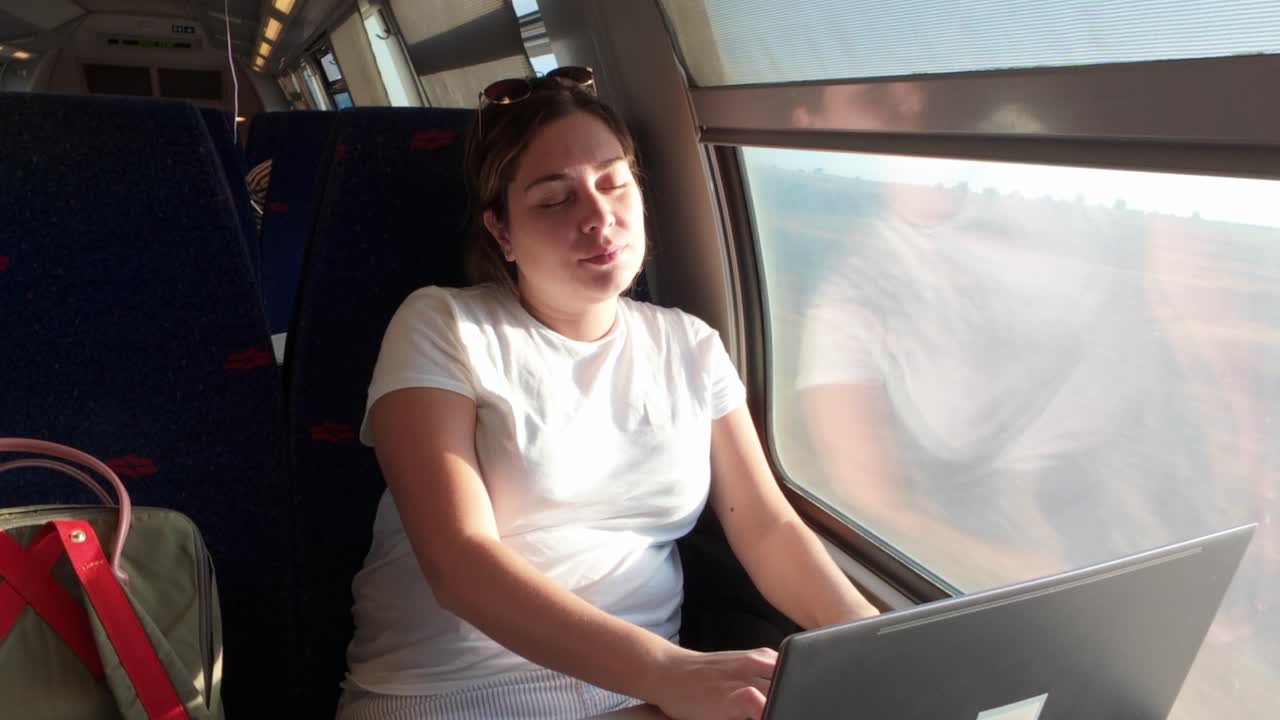 Sleepy Woman Trying to Work on a Laptop During Her Commute