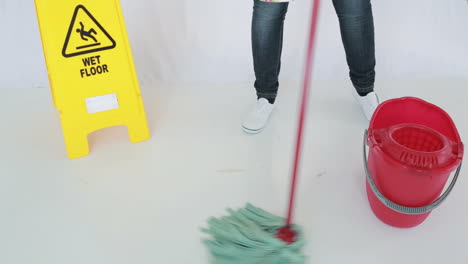 woman cleaning near a caution sign