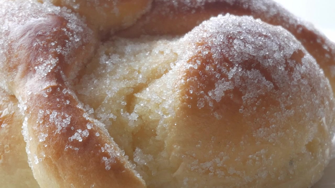 Sweet bread called Bread of the Dead (Pan de Muerto) enjoyed during Day of the Dead festivities in Mexico - closeup slow pan up