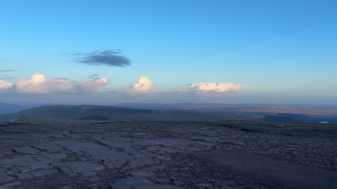 クリビンの岩だらけの山頂高原からは、明るい午後の雲の下に広がるなだらかな丘と、ウェールズの田園地帯を一望できる広大な山岳風景が望める。