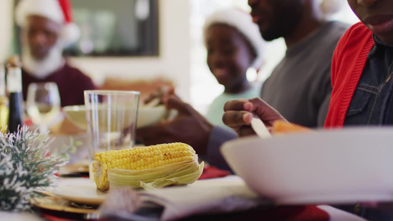 African american girl serving food in plate while sitting on dining table having lunch together at h
