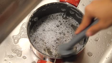 limpiando una olla en el fregadero de la cocina