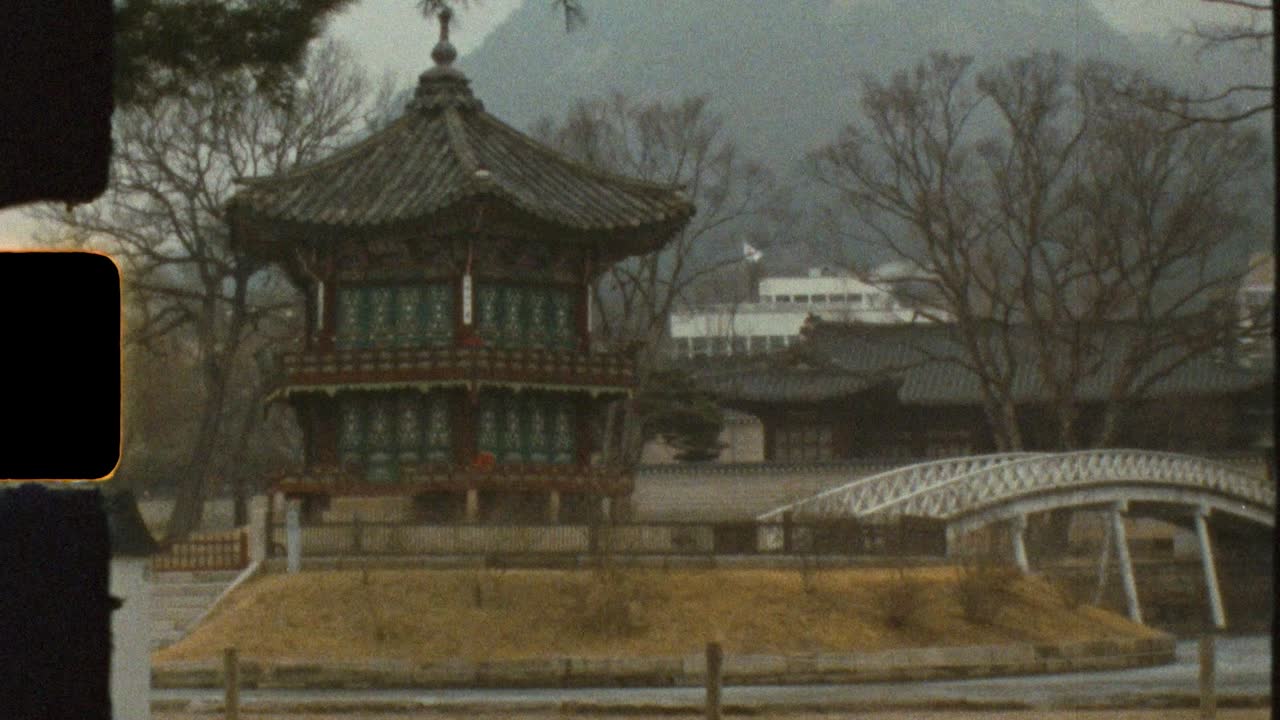 Filmato vintage Super 8 mm dell'edificio del padiglione-tempio Hyangwonjeong su un lago ghiacciato con ponte e alberi sullo sfondo, nel Giardino Segreto del Palazzo Gyeongbokgung, città di Seoul, Corea del Sud, Asia.