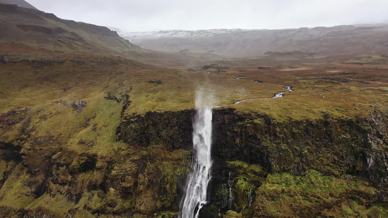 vuelo de drones hacia una cascada arrastrada por el viento en islandia