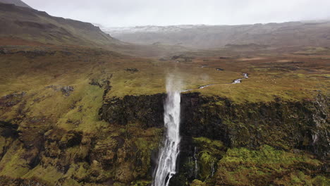 Drone-flight-towards-wind-blown-waterfall-in-Iceland
