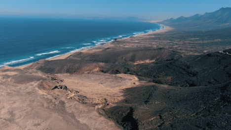 Fantastische-Luftaufnahme-Aus-Großer-Höhe-über-Dem-Naturpark-Cofete-Auf-Der-Insel-Fuerteventura-Und-Wo-Sie-Den-Fantastischen-Strand-Und-Die-Straßen-Sehen-Können,-Die-Auf-Großen-Bergen-In-Der-Gegend-Gebaut-Wurden