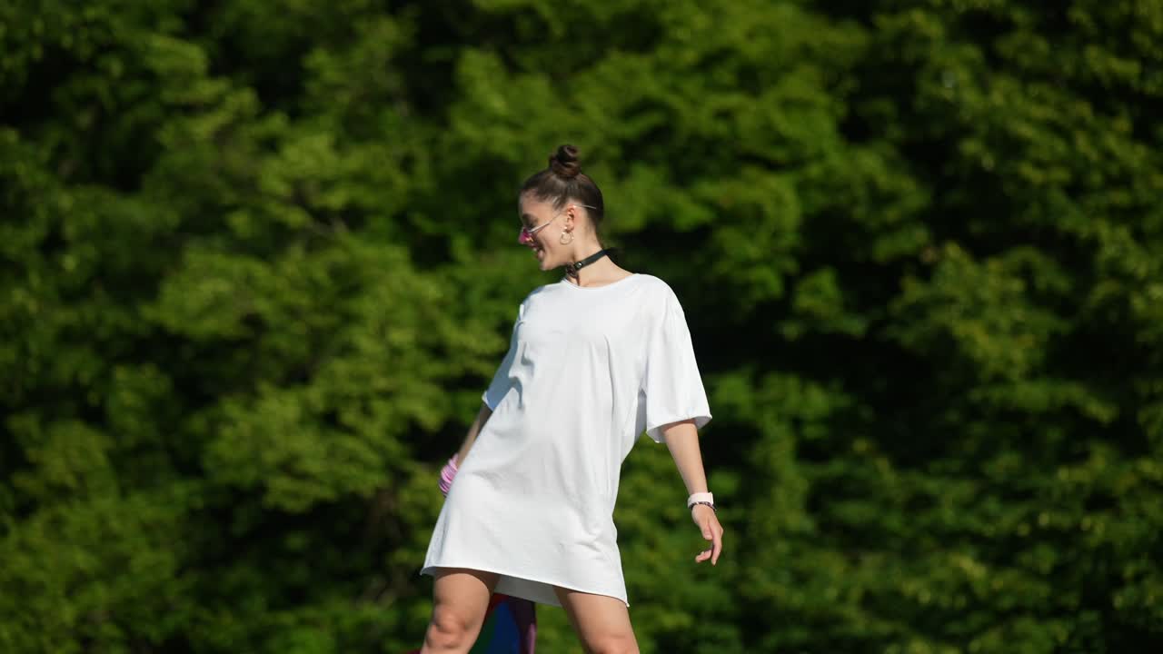 mujer sosteniendo una bandera arco iris en un parque