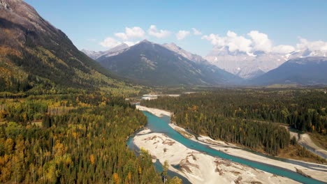 Atemberaubende-Schwenk-Rechts-Weite-Aufnahme-Des-Mount-Robson-Provincial-Parks-Im-Herbst-An-Einem-Tag-Mit-Einer-Mischung-Aus-Sonne-Und-Wolken-Mit-Bergen-Im-Hintergrund-Und-Dem-Fraser-River-Davor,-Umgeben-Von-Wald