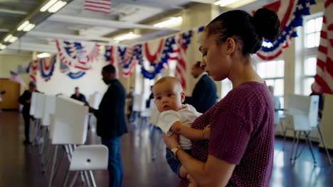 a woman holding a baby at a polling place