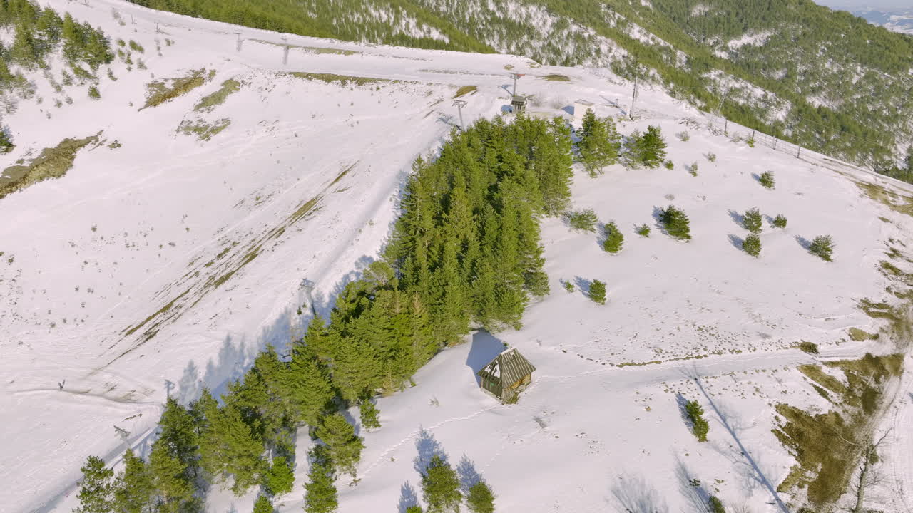 Aerial View of Snowy Mountain Landscape with Pine Trees and Wooden Hut