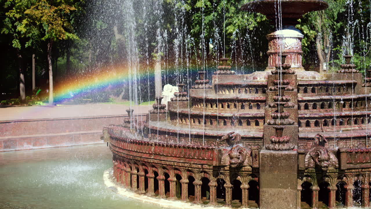 Small rainbow being formed near a water fountain in a park