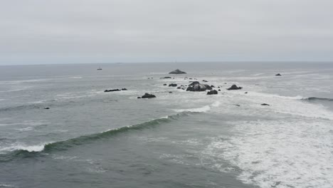 drone aerial over choppy ocean waves toward a fishing boat in the distance on a cloudy day, pacific ocean, oregon