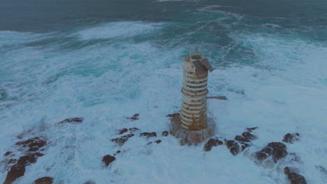 Verträumter-Sonnenuntergang-Am-Leuchtturm-Von-Mangiabarche-Mit-Wellen,-Die-Sein-Fundament-Auf-Sardinien-Streicheln