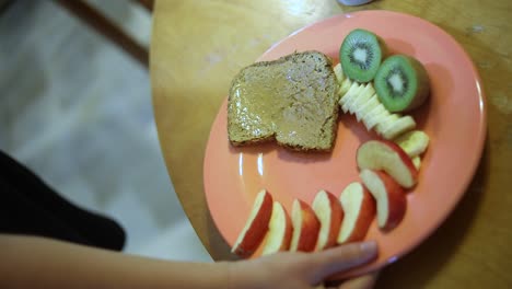 slow motion shot of someone setting a plate full of breakfast food on a wooden table