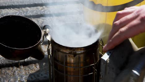 beekeeper preparing smoker for harvesting in apiary