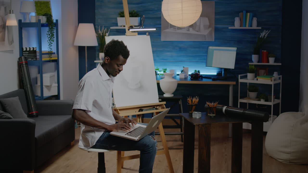 African american artist man searching inspiration on laptop