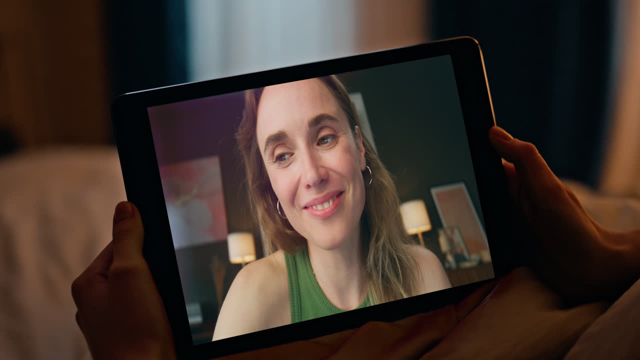 Chica alegre llamando a una conferencia virtual de cerca por la noche en casa. Mejores amigas hablando
