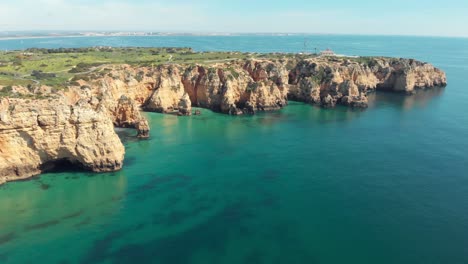 distant view of the ponta da piedade lighthouse and cliffs overlooking atlantic ocean, lagos , algarve