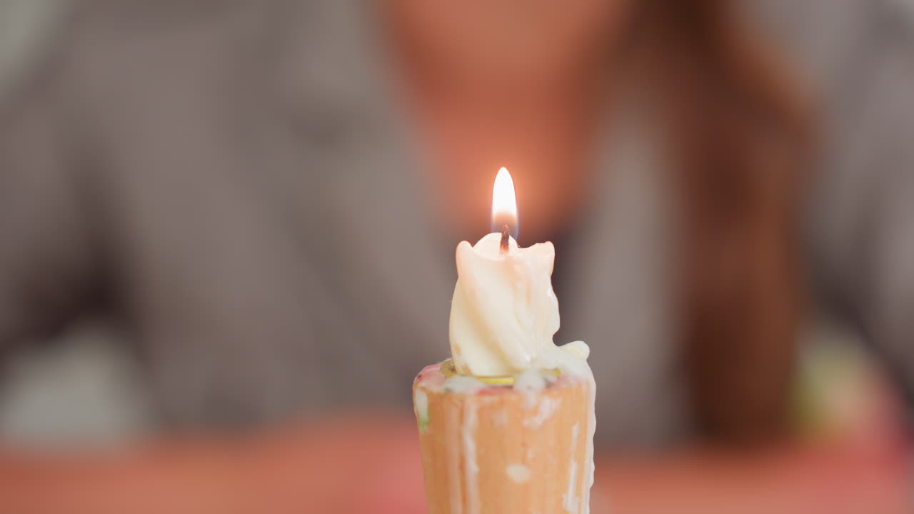 Primer plano de la mano de un adulto encendiendo una vela de cera con un encendedor metálico durante una clase, la mecha prendiendo, derritiendo la cera sobre un soporte de madera, demostración de seguridad, momento de aprendizaje tranquilo