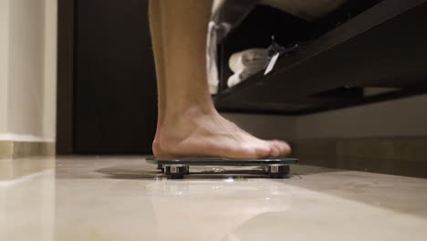 skinny boy steps onto weighing scale, medium