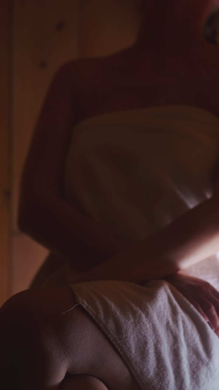 Gentle warmth embraces young woman in sauna. Woman in towel maintains health by spending time in sauna for cleansing body. Relaxing body in calming atmosphere