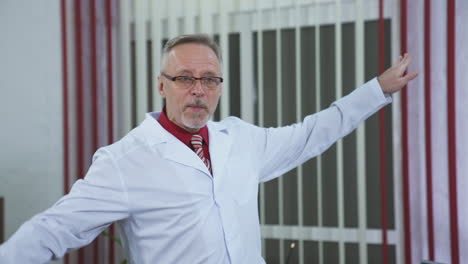 cheerful doctor in medical center. senior male doctor in glasses and medical coat talking and gesticulating a lot in medical office.
