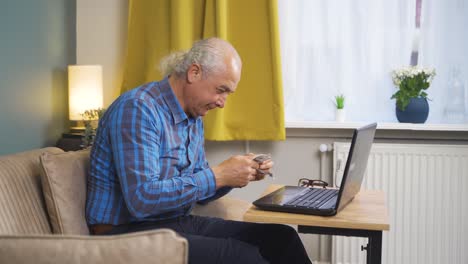 Old-man-counting-money-at-laptop.
